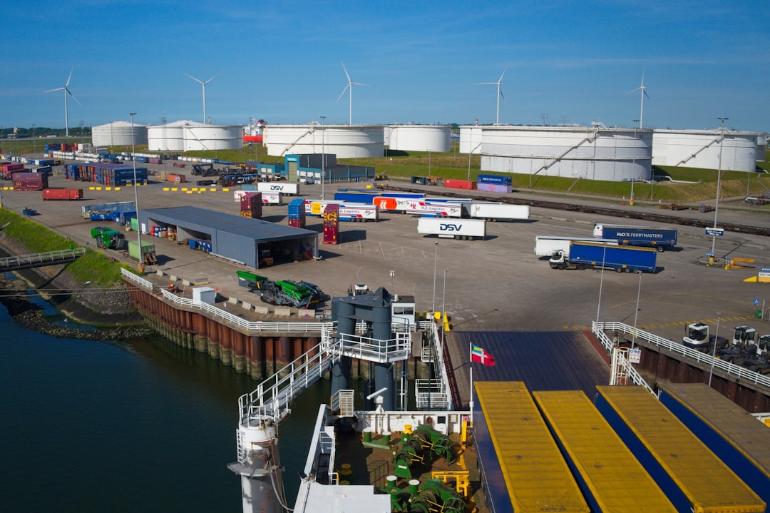 Industrial port with a ferry, trucks, and storage tanks.