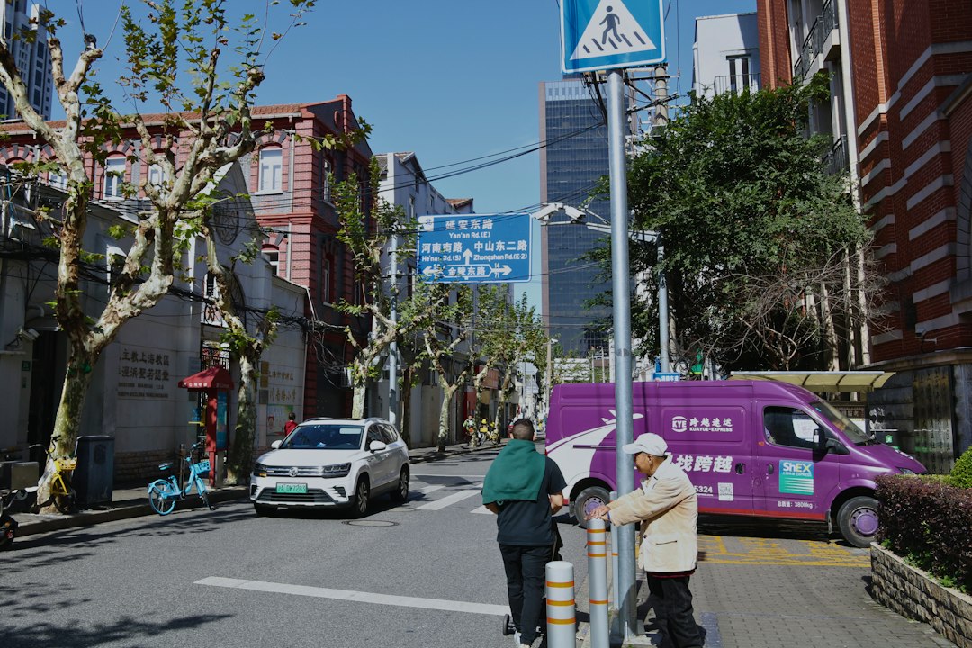 People cross street near purple van and cars