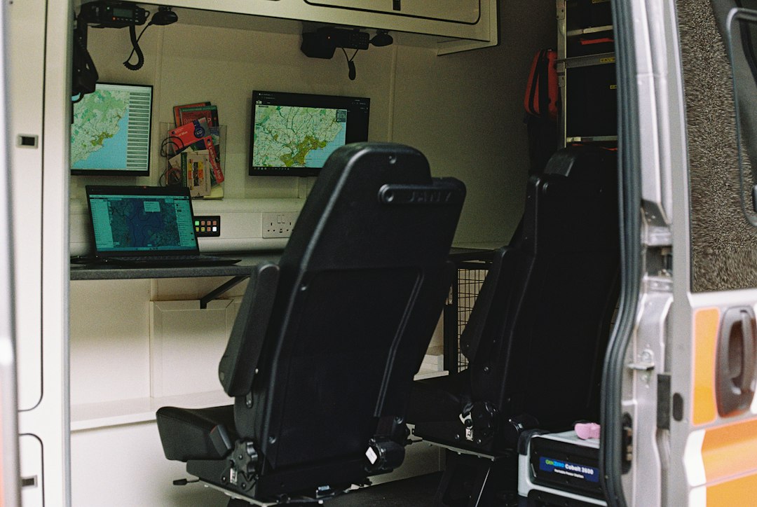 Two black seats inside a mobile command vehicle with monitors displaying digital maps